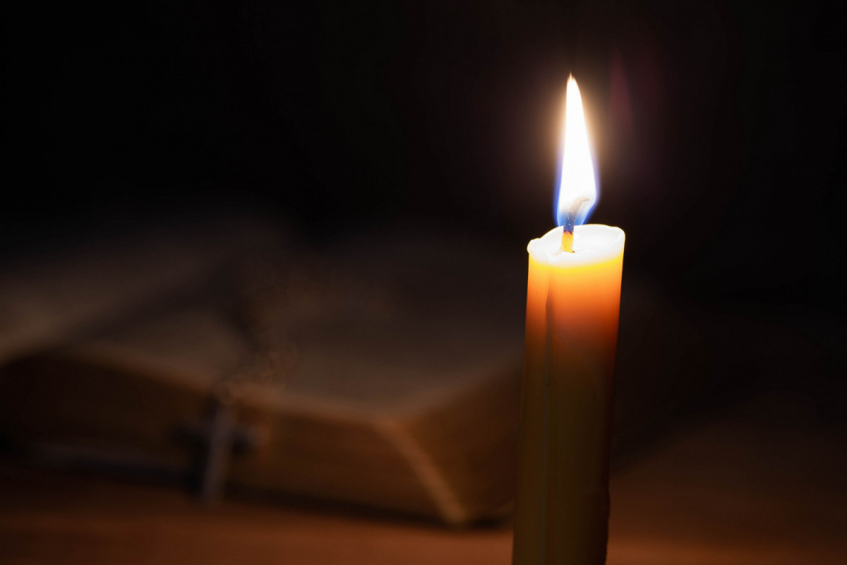 Bible and candle on old oak wooden table