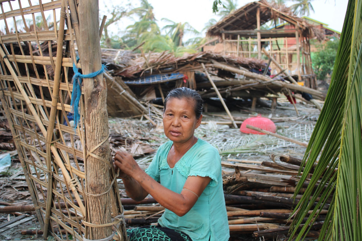 Imagen de una mujer con su casa en ruinas, en Wet Myaung Village, Mrauk.